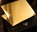 Gold MacBook Pro open on a black leather presentation box